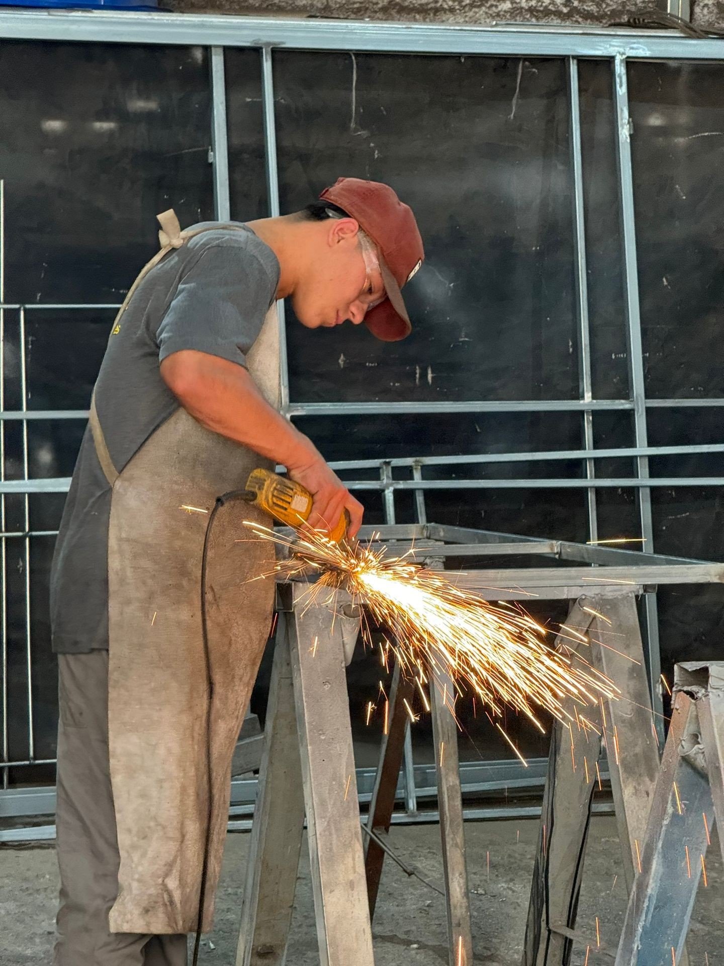 Person wearing protective gear using an angle grinder with sparks flying in a workshop.